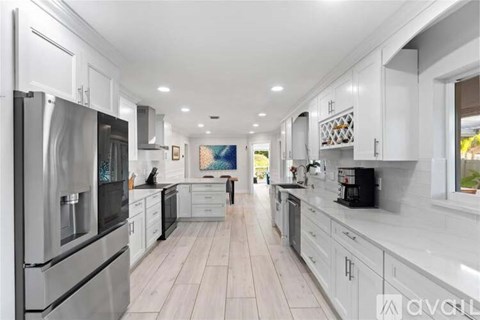 A modern kitchen with white cabinets and stainless steel appliances.