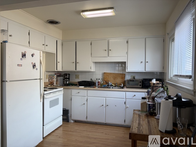 A kitchen with white cabinets and a refrigerator.