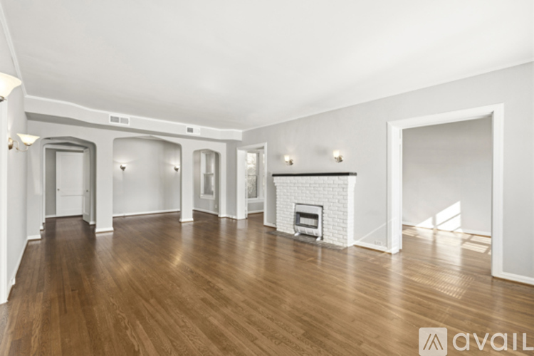 A spacious room with wooden floors and a fireplace.