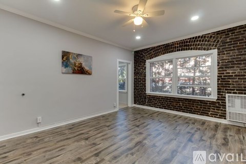 A room with a ceiling fan and a painting on the wall.