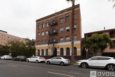 Cars parked in front of a building with a tree in front of it.