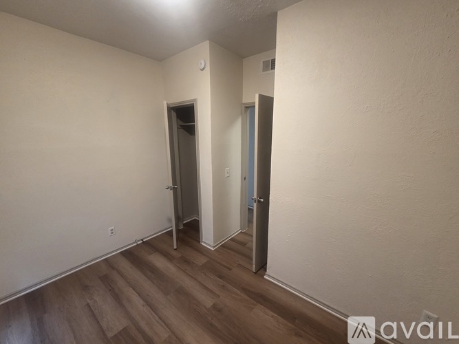 A room with a wooden floor and two doors.