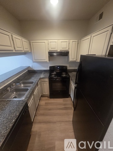 A kitchen with black appliances and white cabinets.