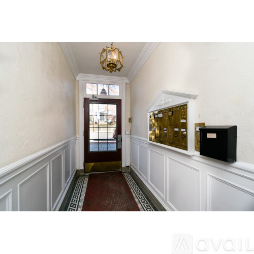 A hallway with a red carpet and a black mailbox.