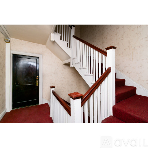 A staircase with red carpet and white railings.