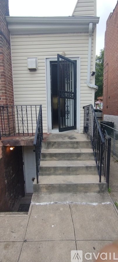 A white building with a black gate and steps leading up to it.