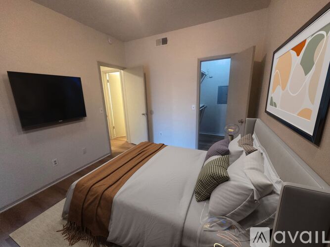 A bedroom with a bed, a television, and a painting on the wall.