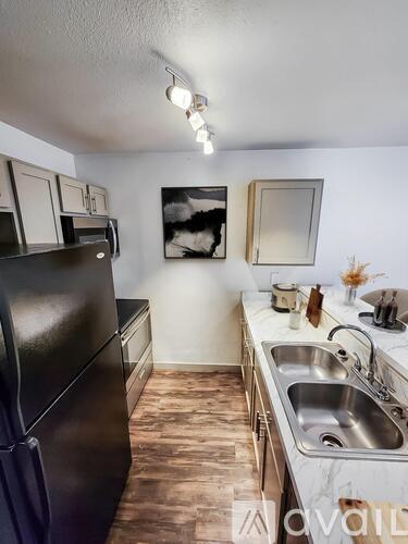 A kitchen with a black fridge, a sink, and a counter with a vase of flowers on it.