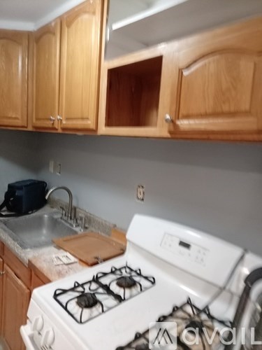 A kitchen with a white stove and wooden cabinets.