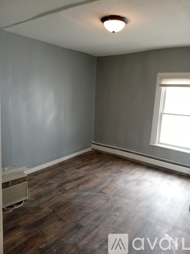 A room with wooden flooring and a window.