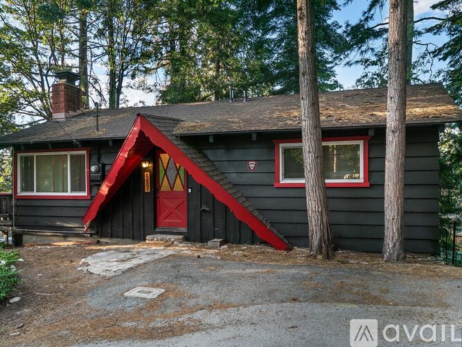 A black house with a red door and a red window.