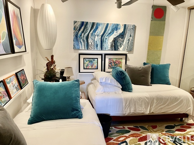 A bedroom with two beds and a painting on the wall.