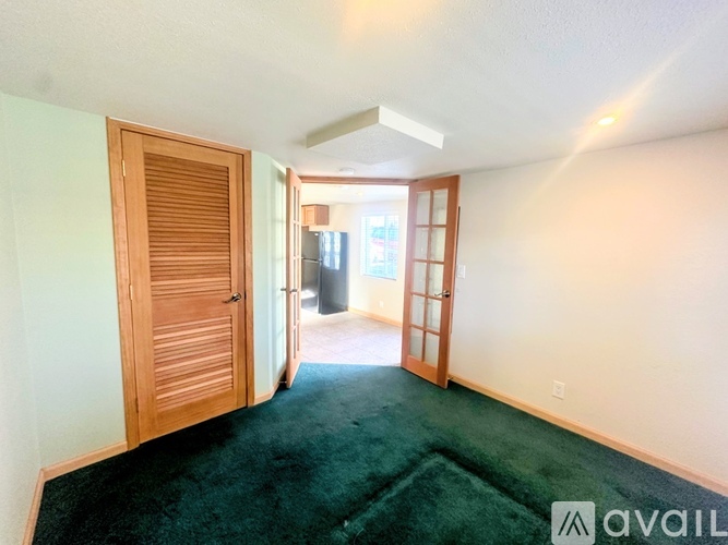 A room with a green carpet and a wooden door.