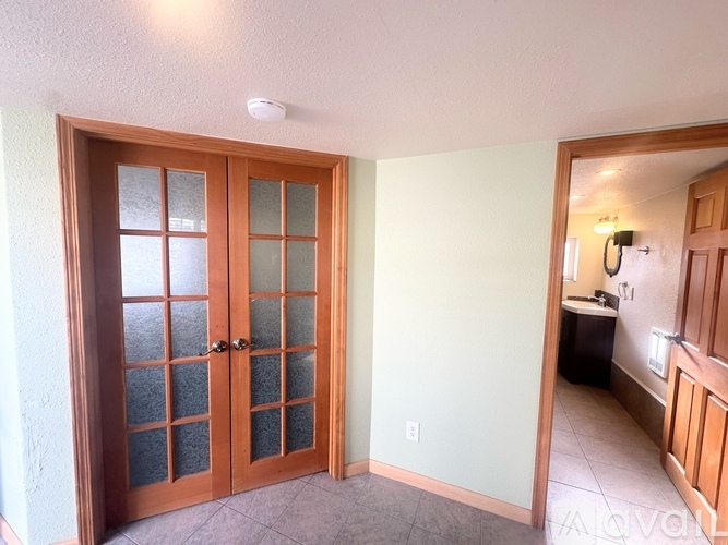 A room with a glass door and a kitchen in the background.
