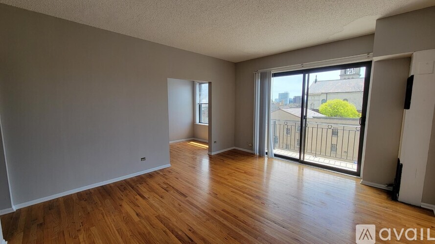 A room with wooden floors and a large window with a view of the city.