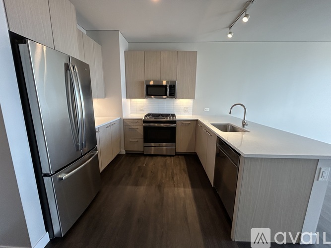 A modern kitchen with a stainless steel refrigerator and wooden flooring.