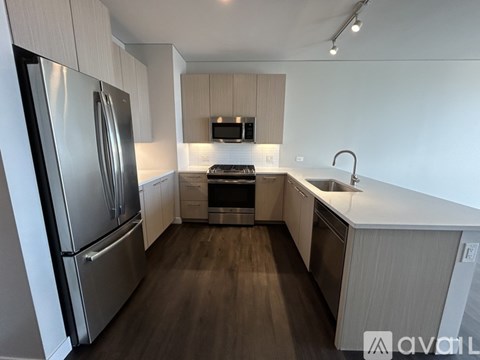 A modern kitchen with a stainless steel refrigerator and wooden flooring.