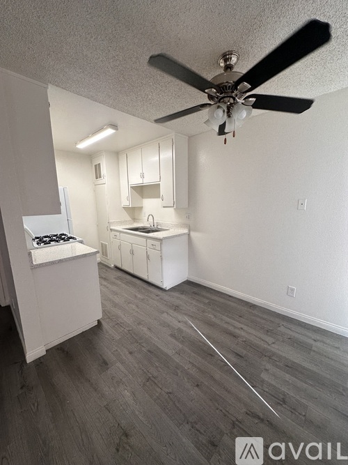 A room with a fan, a stove, and a sink.