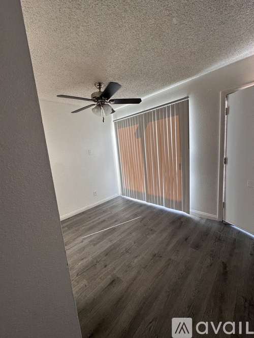 A room with a ceiling fan and sliding glass doors.