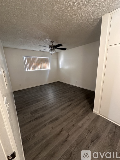 A room with a ceiling fan and wooden flooring.