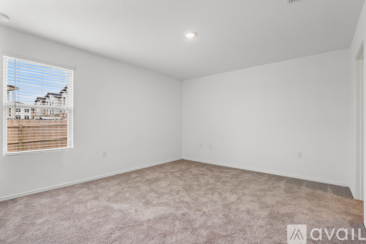 A room with a window showing a building outside and a carpet on the floor.