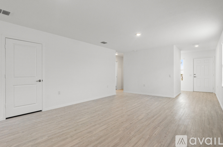 A spacious room with wooden flooring and white walls.