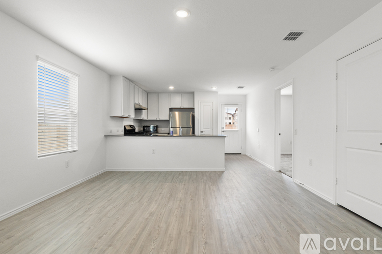 A spacious kitchen with white cabinets and a wooden floor.