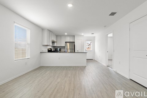 A spacious kitchen with white cabinets and a wooden floor.