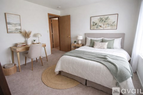 A bedroom with a bed, desk, chair, and window.