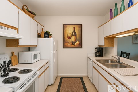 A kitchen with white cabinets and a painting of wine and fruit on the wall.