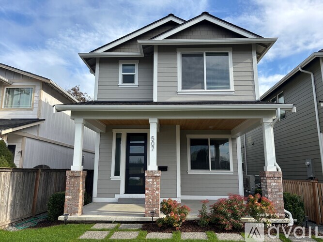 A two-story house with a front porch and a garage door.