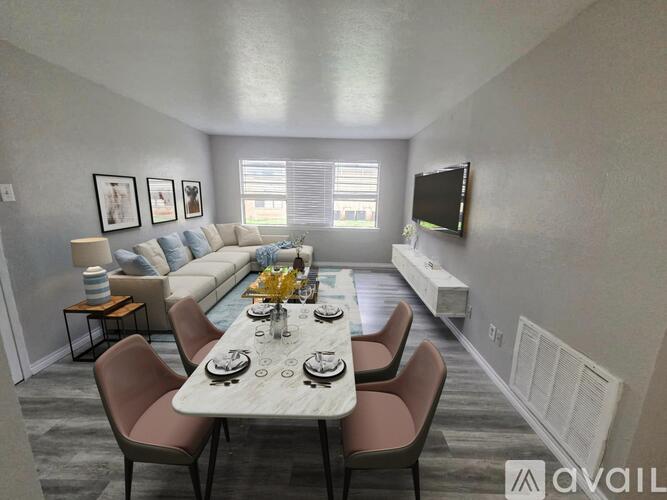 A dining room with a table set for six and a couch in the background.