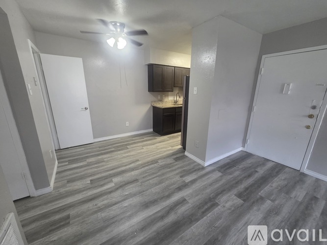 A room with a ceiling fan and a kitchenette in the corner.
