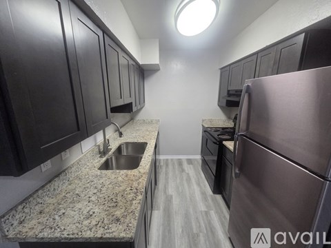 A kitchen with dark wood cabinets and a granite countertop.