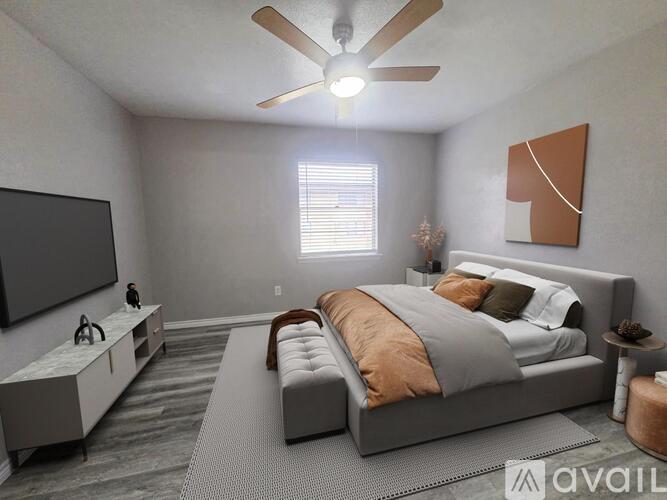 A bedroom with a large bed, a television, and a ceiling fan.