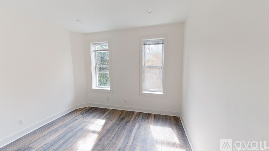 A room with two windows and wooden flooring.