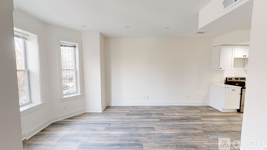 A spacious room with wooden flooring and white walls.