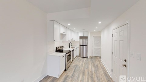 A kitchen with white cabinets and a wooden floor.