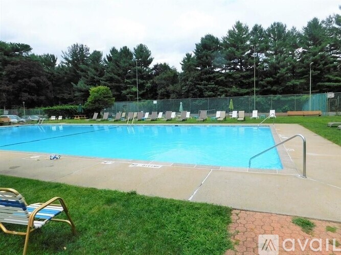 A pool surrounded by a fence and trees.