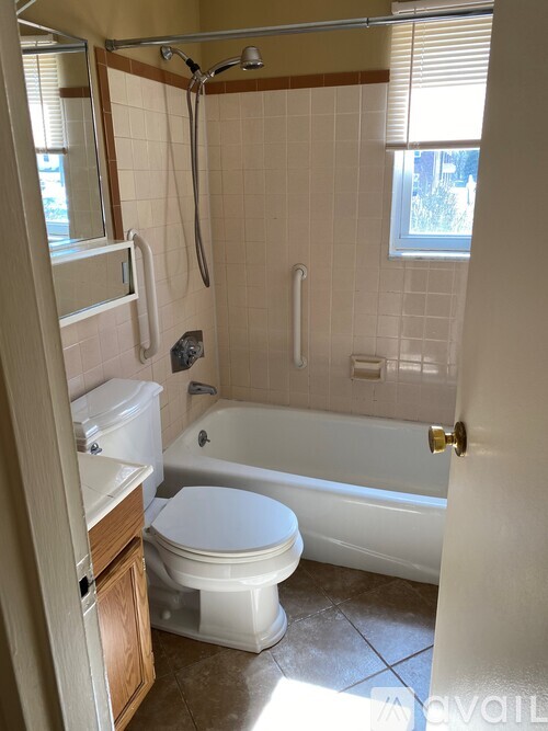 A white toilet is in a bathroom with a tub and shower.
