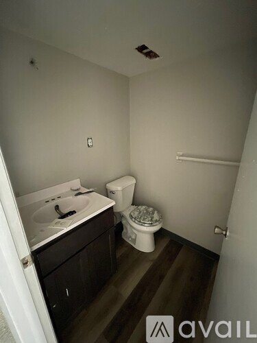 A bathroom with a toilet, sink, and wooden floor.