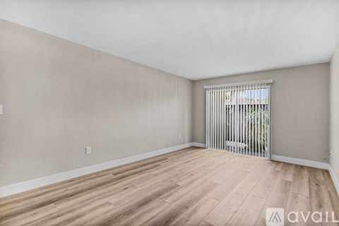 A room with wooden flooring and a window with blinds.