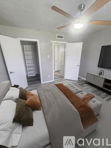A bedroom with a bed, a television, and a ceiling fan.