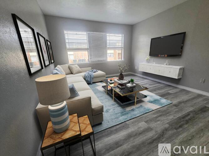 A living room with a white couch, a coffee table, and a television on the wall.