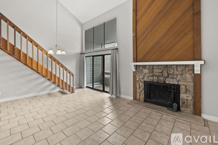 A living room with a stone fireplace and a tiled floor.