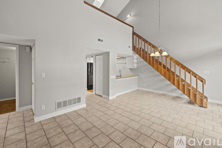 A spacious room with a tiled floor and a wooden staircase.