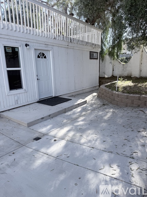 A white building with a door and window is surrounded by a white fence.