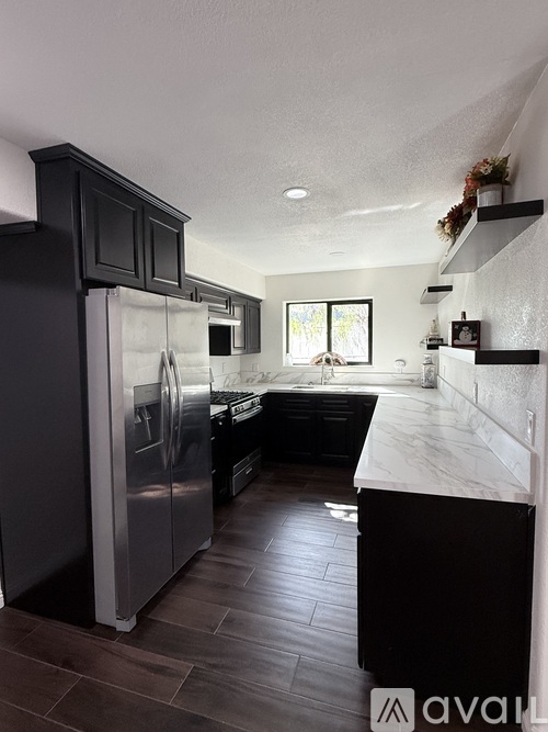 A kitchen with a black fridge and a black counter top.