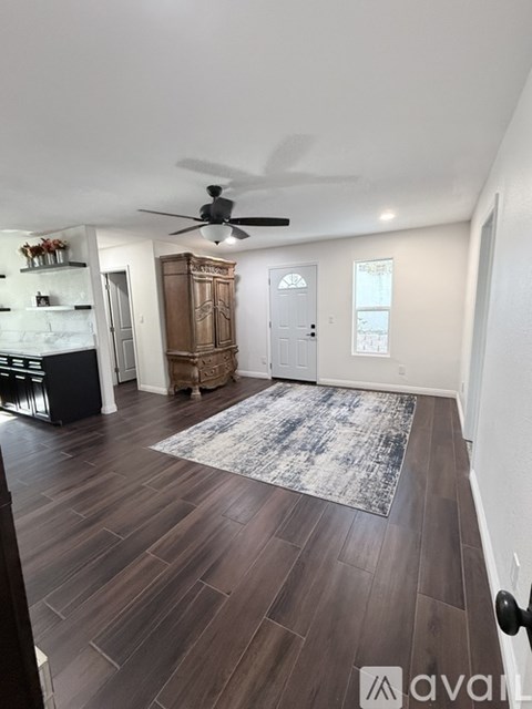 A living room with a ceiling fan and a rug on the floor.