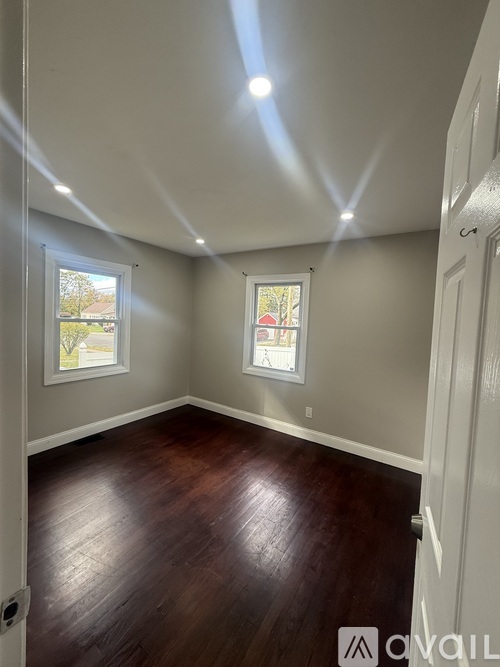 A room with wooden floors and two windows.